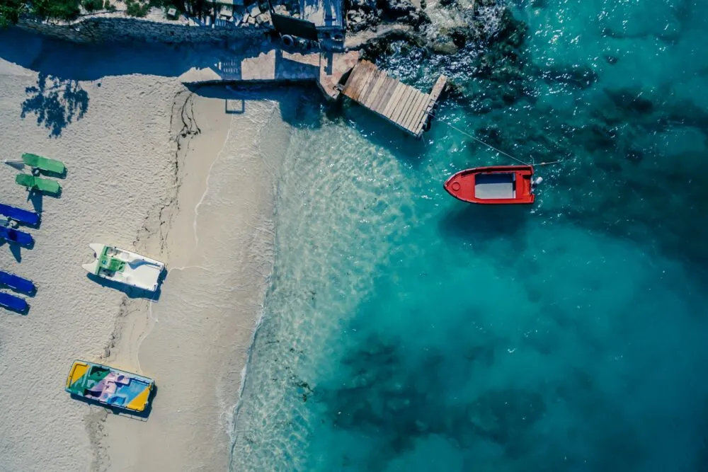 Een strand in Albanië met een rode boot in bet water